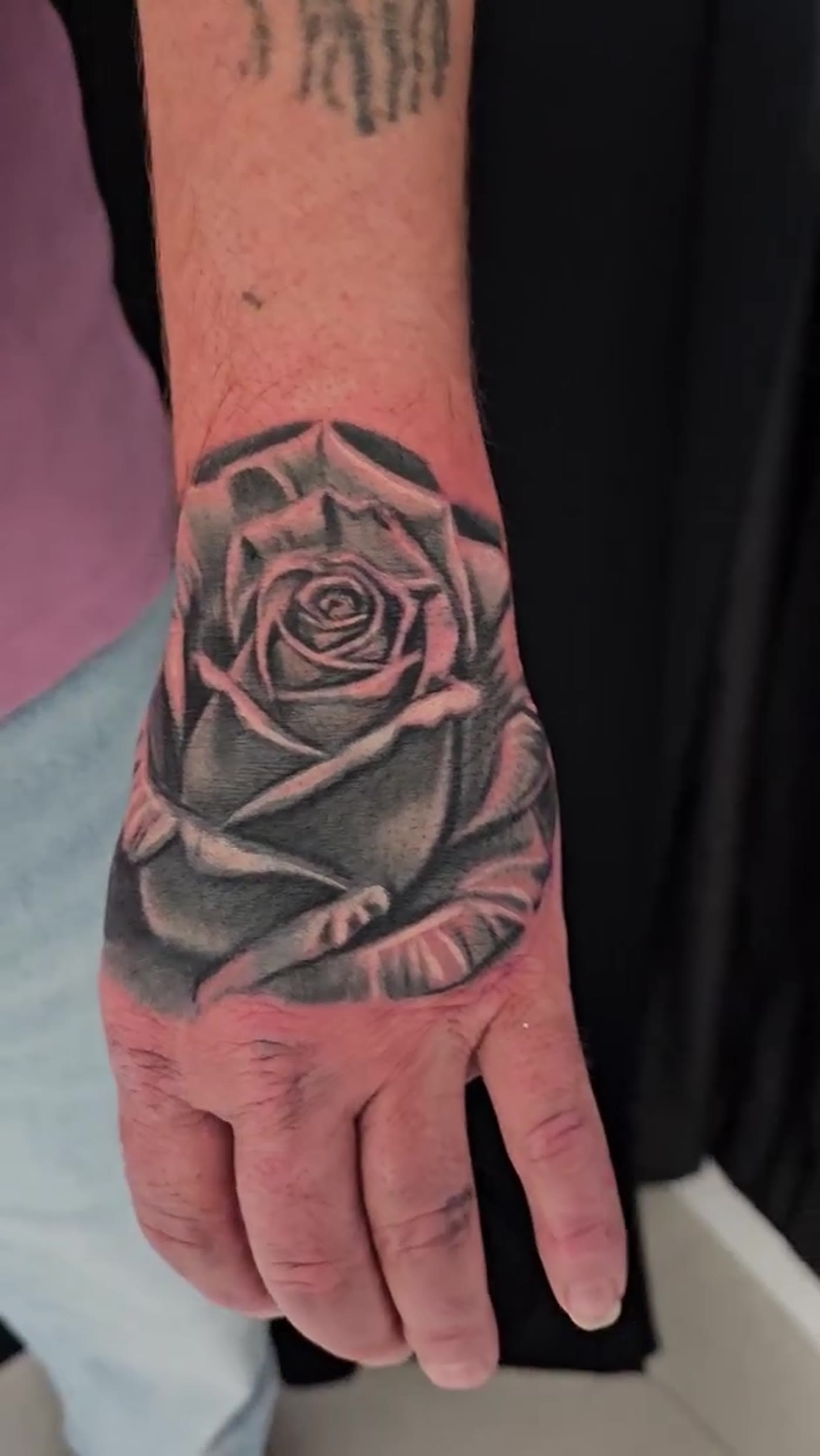 Black-and-grey rose cover-up on the hand by Guy Abergel