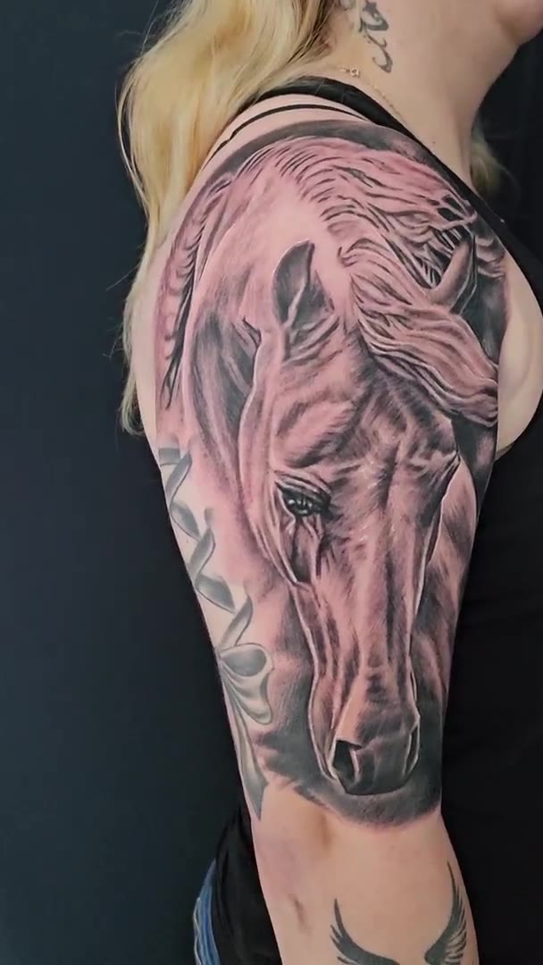 Black-and-grey realism horse tattoo on the upper arm by Guy Abergel